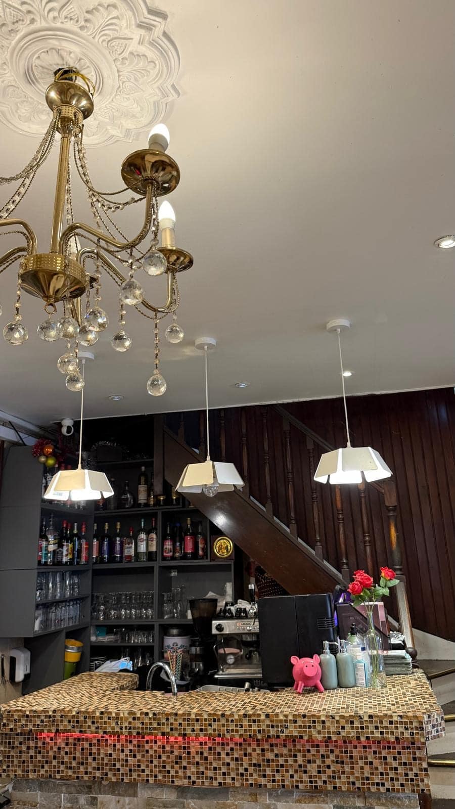 Le lustre en cristal devant le bar, ses bouteilles et les suspensions blanches.