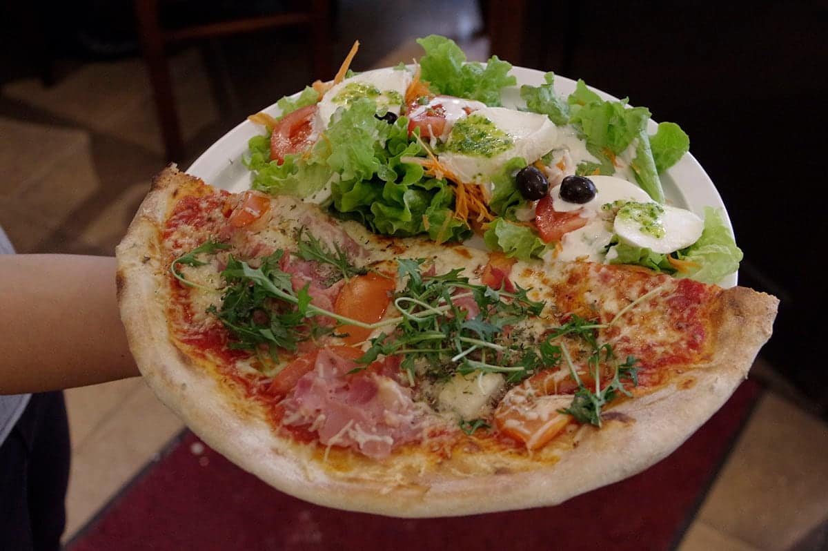 Assiette Light : une demi-pizza et sa salade garnie de tomates et de mozzarella.