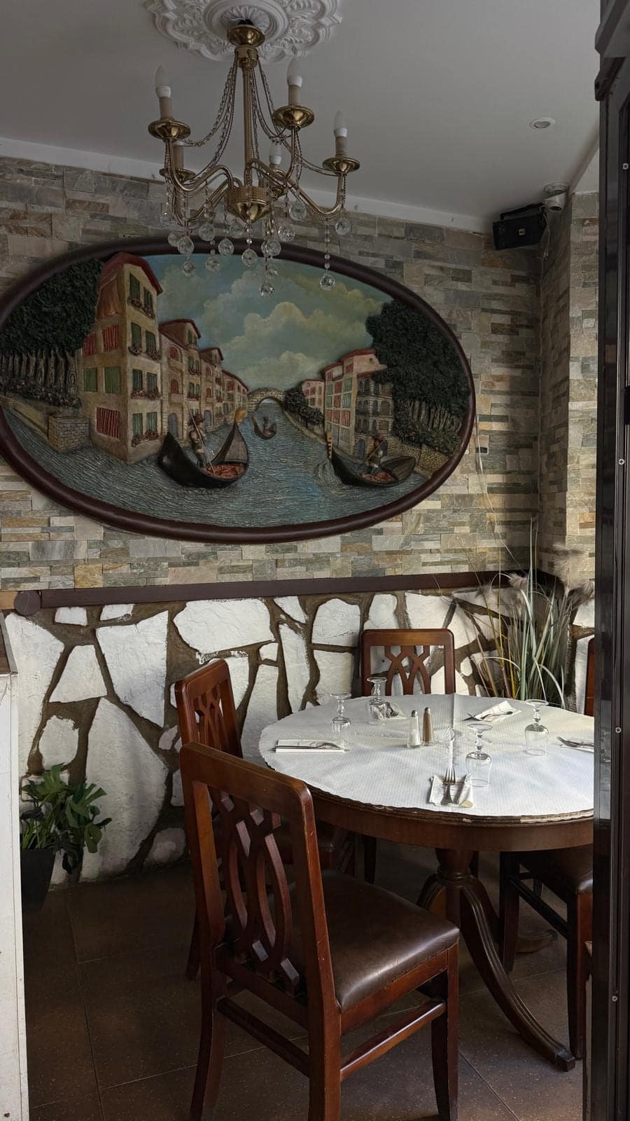 Le bas-relief ovale d’un canal de Venise au-dessus d’une table ronde, lustre en cristal.