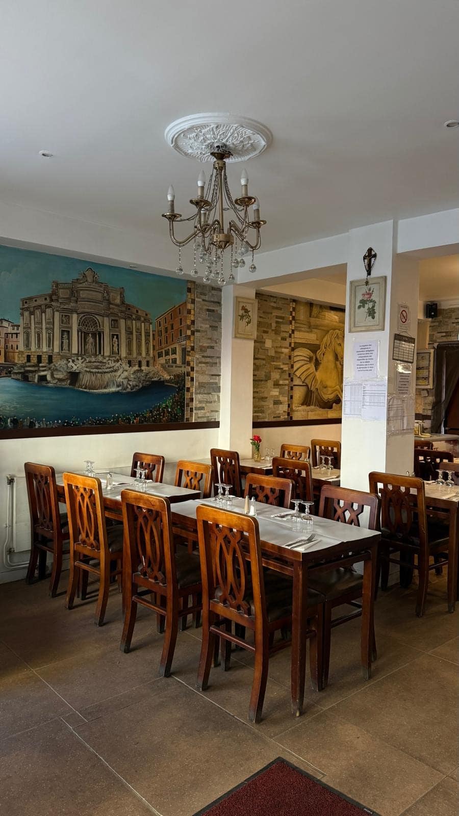 La salle en journée : tables en bois clair et fresque de la fontaine de Trevi.