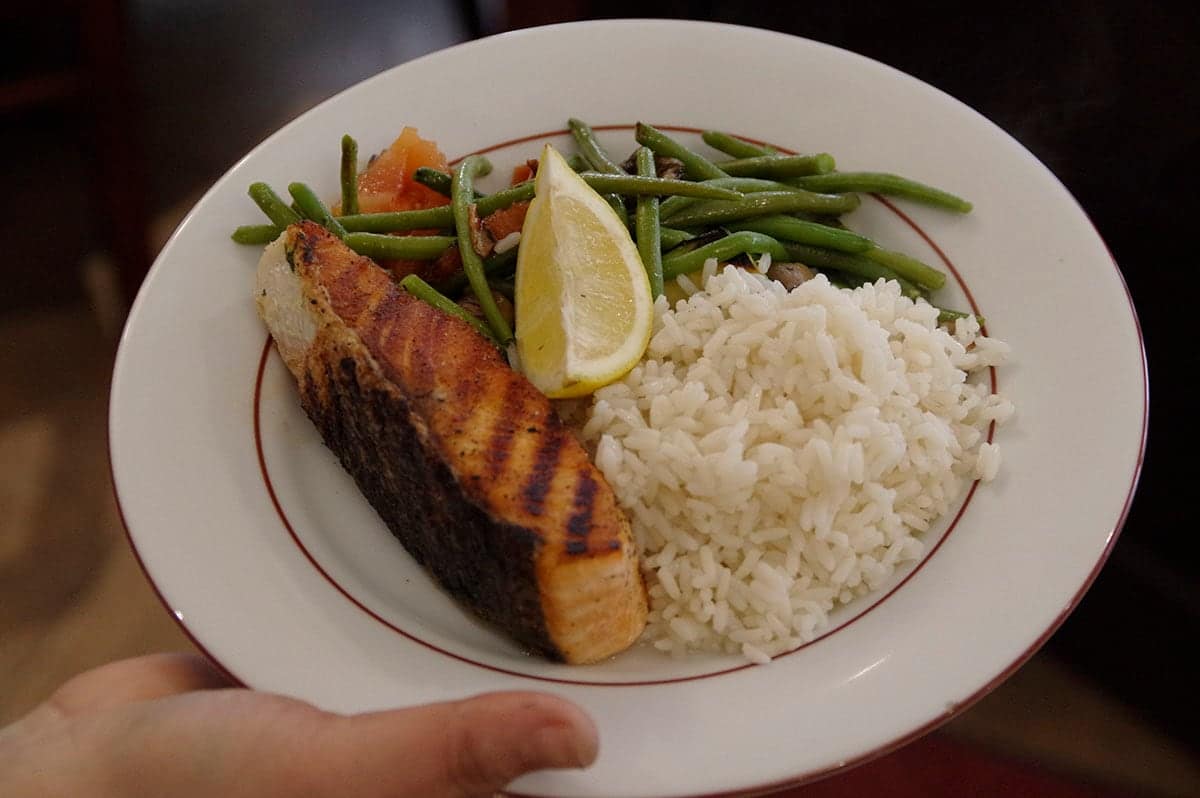 Pavé de saumon grillé, haricots verts, riz et quartier de citron.