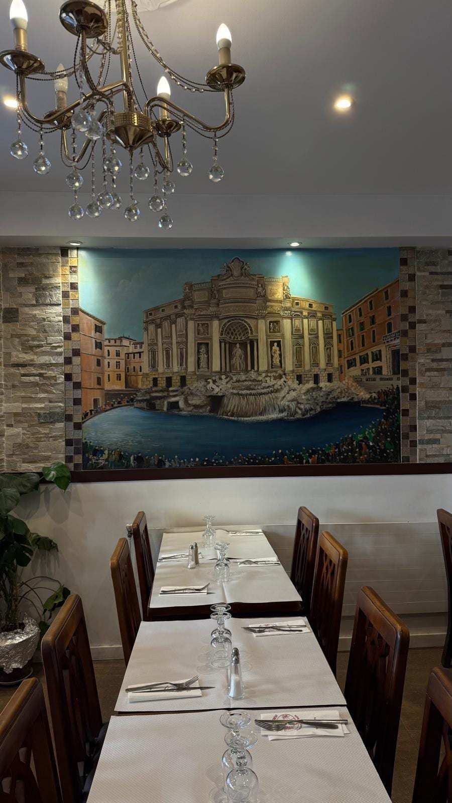 La fresque de la fontaine de Trevi entre deux pans de pierre, sous un lustre en cristal.