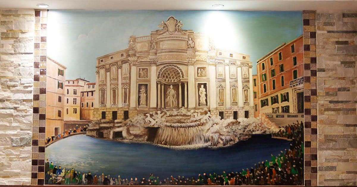 La grande fresque de la fontaine de Trevi peinte sur le mur de la salle, entre deux pans de pierre.
