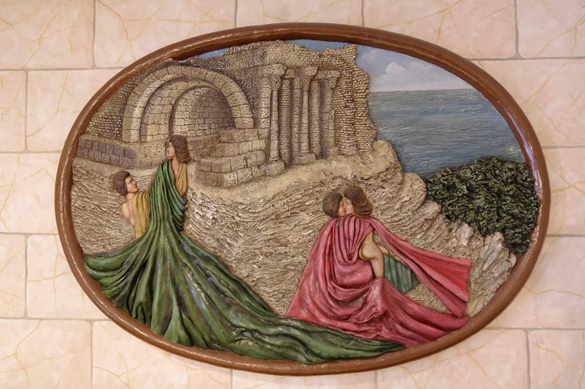 Bas-relief ovale peint : deux personnages drapés devant des ruines antiques et la mer.